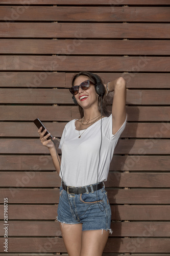 Excited lady listening to music near lumber wall