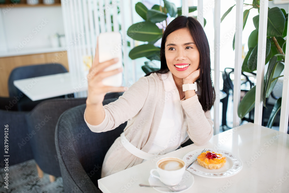 technology and people concept - happy asian woman with cake and coffee taking selfie by smartphone at cafe technology and people concept - happy asian woman with cake and coffee taking selfie by smartphone at cafe