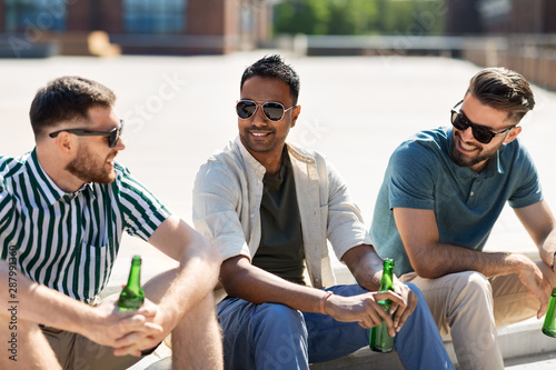 leisure, male friendship and people concept - happy men or friends drinking beer and talking on street in summer