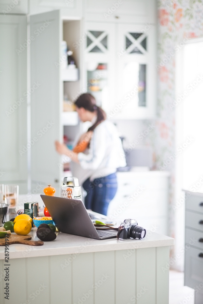 Working mother with daughter preparing for blog in kitchen at home Working mother with daughter preparing for blog in kitchen at home
