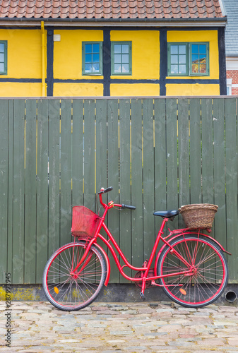 Red bicycle against a green fence in the old part of Ribe, Denmark
