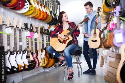 Teenagers examining guitars in shop