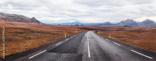 Iceland. Panoramic landscape of Icelandic volcanic nature with asphalt road curved away over horizon. Traveling by Iceland background. Road trip concept.