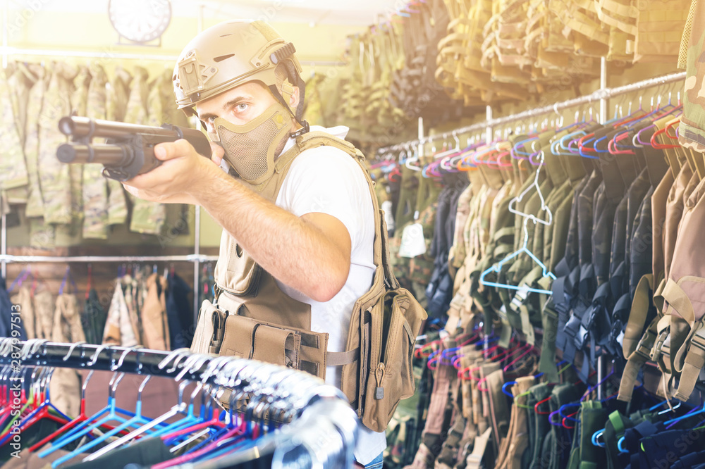 adult guy in military equipment with weapon in army shop