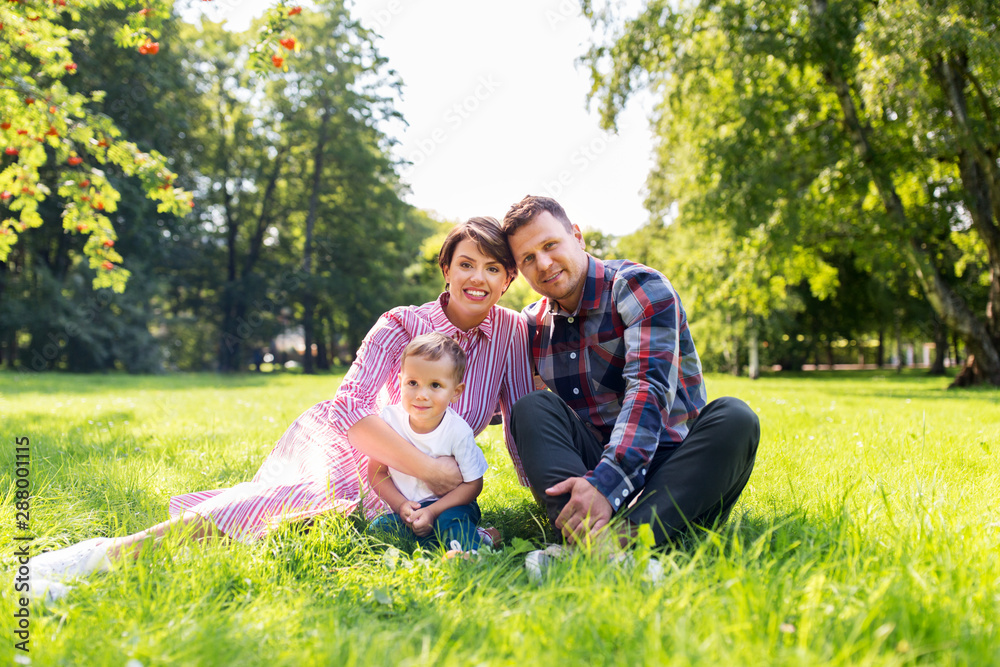 Fototapeta premium family, leisure and people concept - happy mother, father and little son at summer park