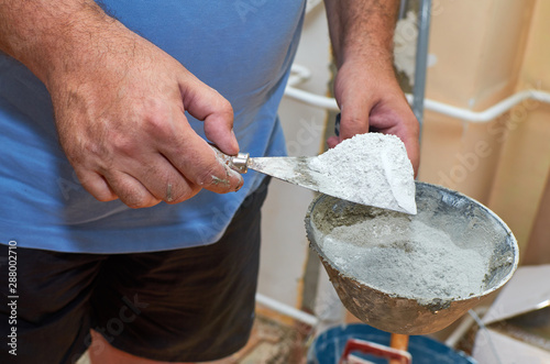 Valokuva Man holding scraper and plasterer's scoop with gypsum powder while preparing it