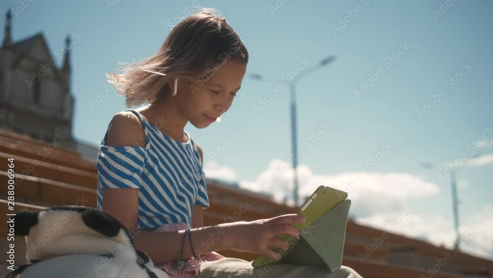 Little girl smile and play in tablet in cafe drink milkshake and dooing homework. Working girl smile and play computer