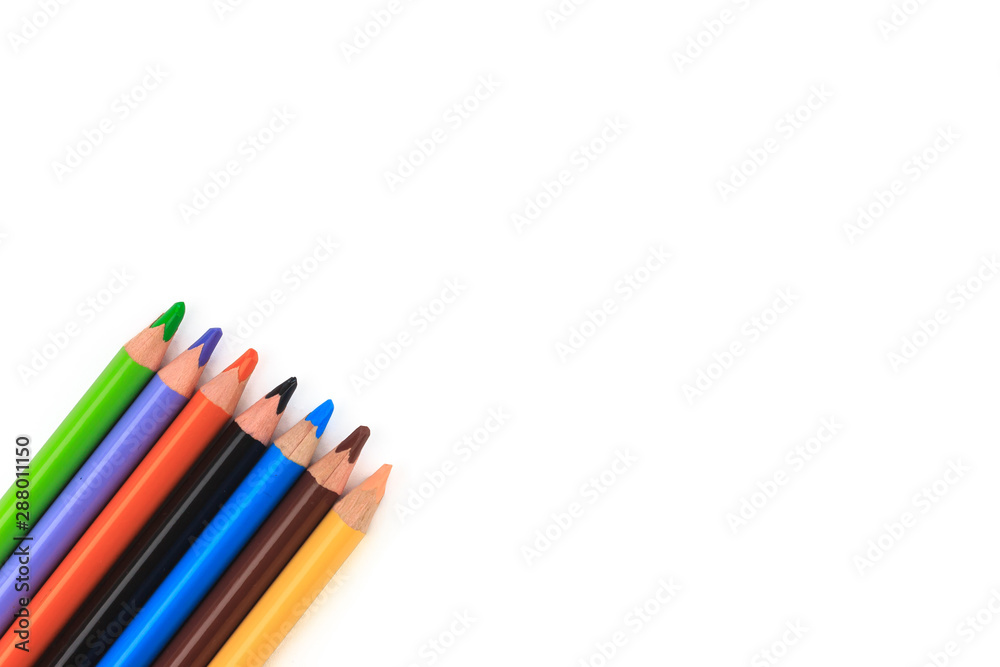Color pencils with copy space on isolated white background. Green, purple, orange, black, blue, brown and beige painting pencils or crayons on left corner of the photo. Education frame concept.