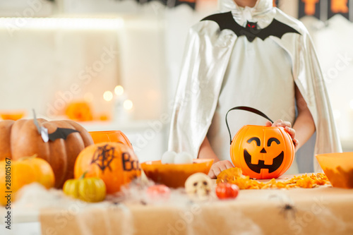 Close-up of boy dressed in costume standing near the table with pumpkins and lanterns at Halloween party © AnnaStills
