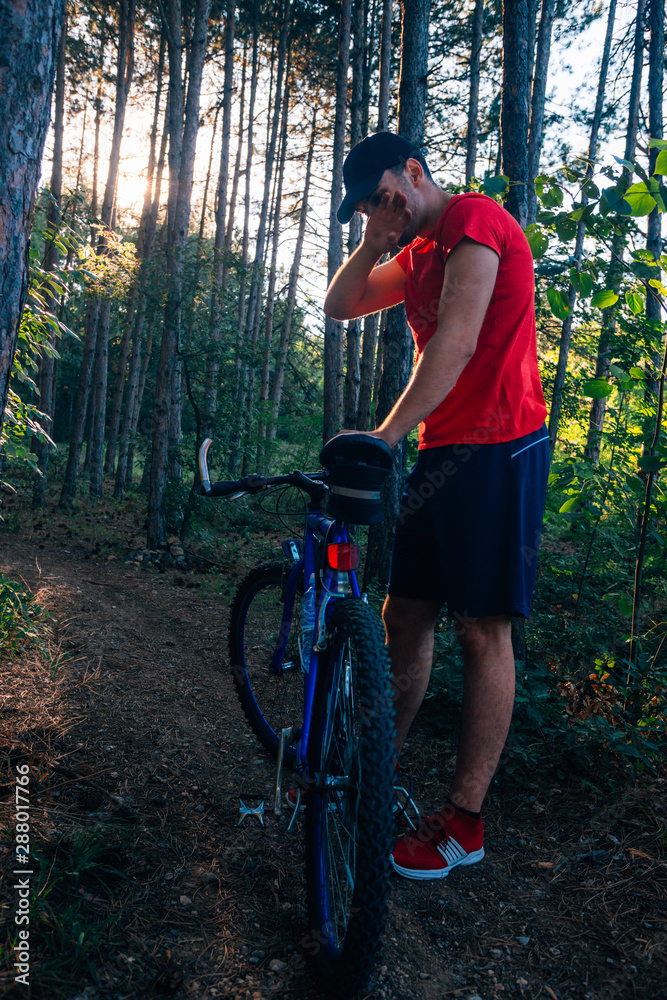 Fototapeta premium Portrait of a handsome mountain biker drinking water while wearing his baseball cap (hat).