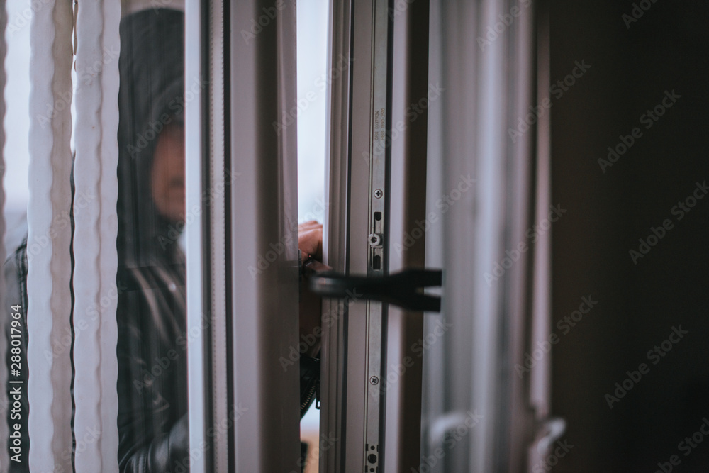 A thief trying to get into a house by the backdoor A thief trying to get into a house by the backdoor
