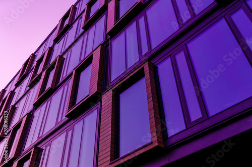 Modern office building in the evening. Facade purple mirror