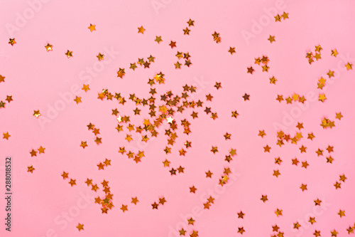 Golden glitter stars on pink background. Festive pastel backdrop.