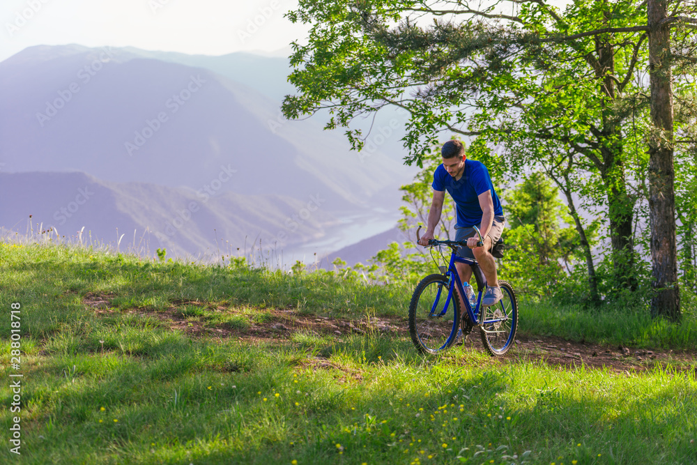 Adventurous mountain biker riding his bike fast through the woods ( forest ) while enjoying the green nature.