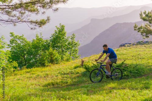 Adventurous mountain biker riding his bike fast through the woods ( forest ) while enjoying the green nature.