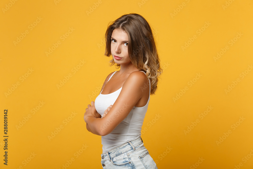 Side view of displeased young woman girl in light casual clothes posing isolated on yellow orange wall background studio portrait . People lifestyle concept. Mock up copy space. Holding hands crossed. Side view of displeased young woman girl in light casual clothes posing isolated on yellow orange wall background studio portrait . People lifestyle concept. Mock up copy space. Holding hands crossed.