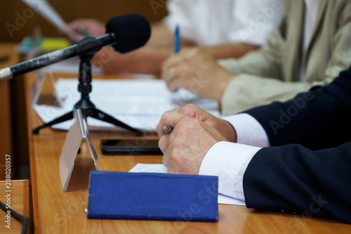 Fotografía A man in a jacket sits in front of a microphone during a report