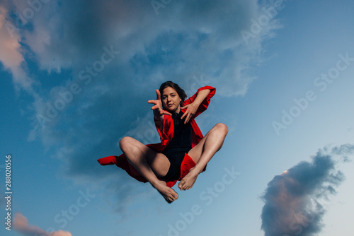 Happy healthy woman leaping over blue sky on summer vacation