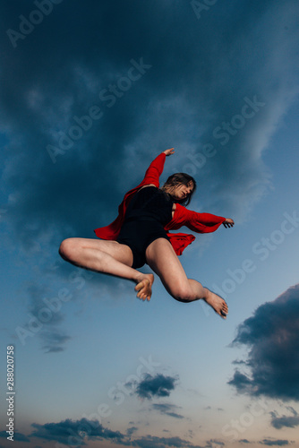 Happy woman jumping at blue cloudy sky