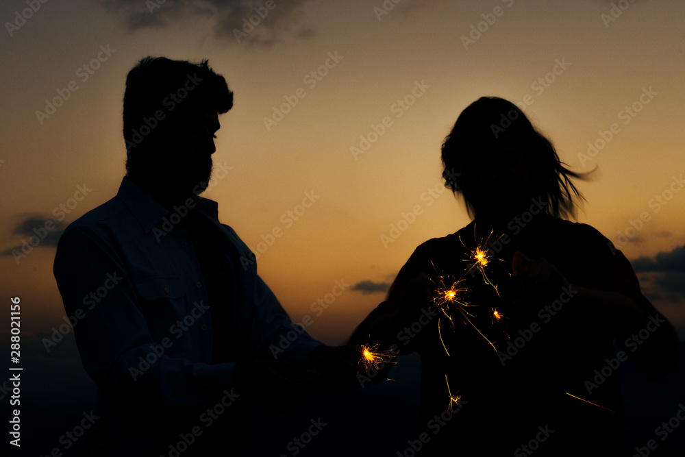 Picture showing young silhouette couple having fun with sparklers