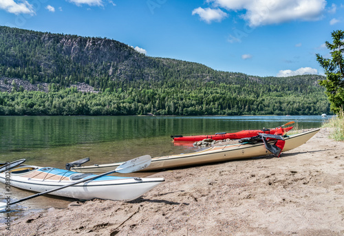 Three kayaks -white, red and beige colored stranded on the small Island's beach, after paddling from Doksta to Kramfors Island, High Coast, Vasternorrland County Sweden photo