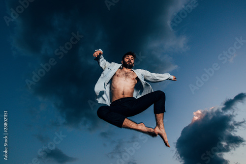 Young man break dancing against cloudy sky