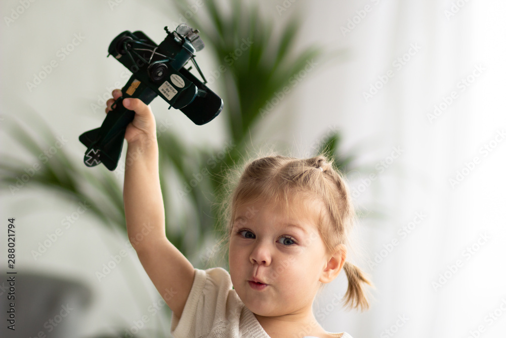Φωτογραφία Portrait of little girl playing with the toy plane and looking at camera