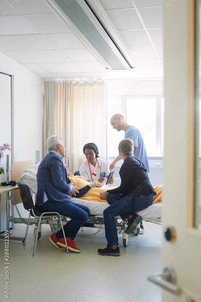 Healthcare workers discussing with patient and her friends in hospital ward Healthcare workers discussing with patient and her friends in hospital ward