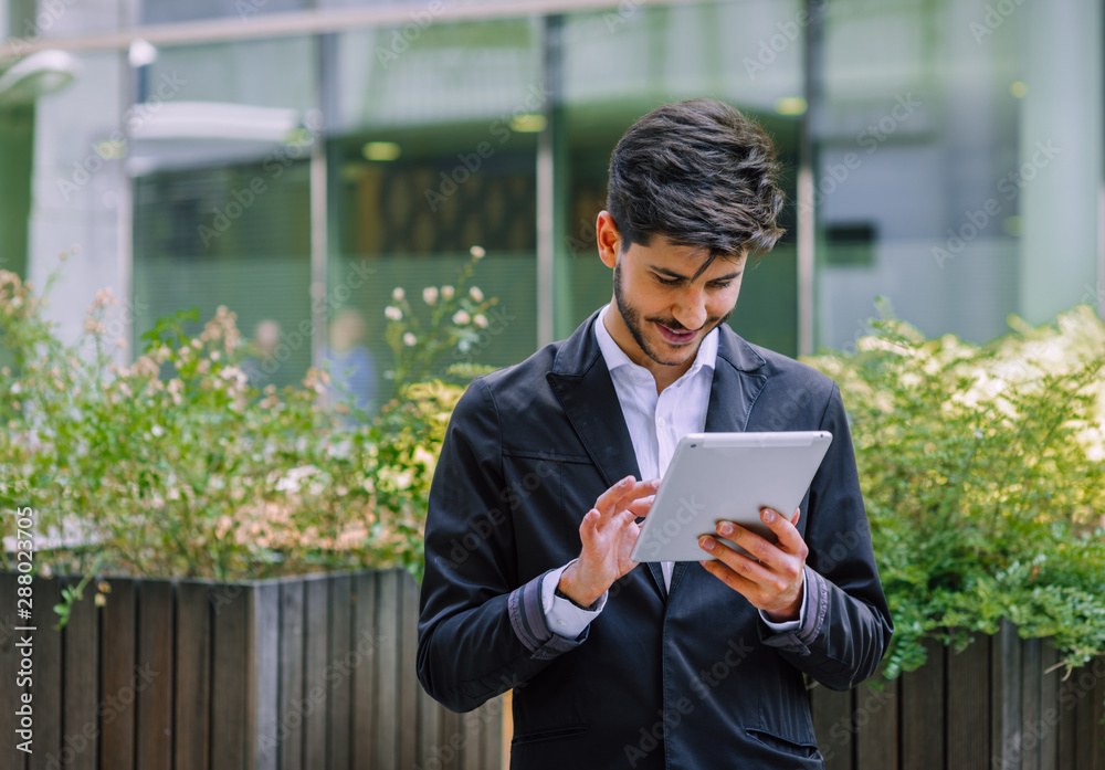 Businessman in suit working on pc tablet while standing outdoor Businessman in suit working on pc tablet while standing outdoor