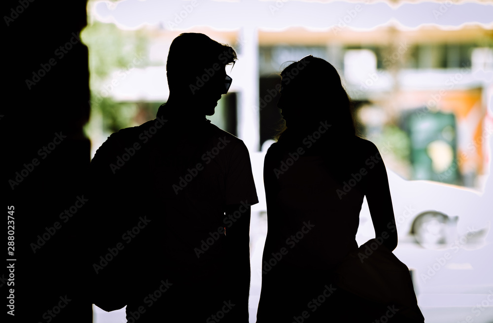 Silhouette of couple with shopping bags holding hands while walking on street