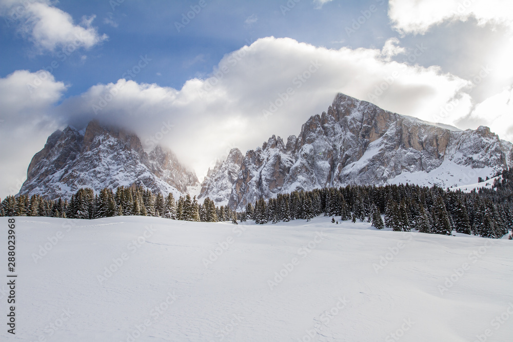 Langkofel and Plattkofel Panorama in the Dolomites from Monte Pana. Mountain Peaks hidden by Clouds. Snow covered Sassolungo and Sassopiatto.