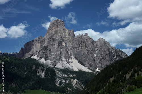 Sassongher above Corvara in the Dolomites, Epic Mountain in South Tirol, Südtirol with some clouds above and dark forest beneath