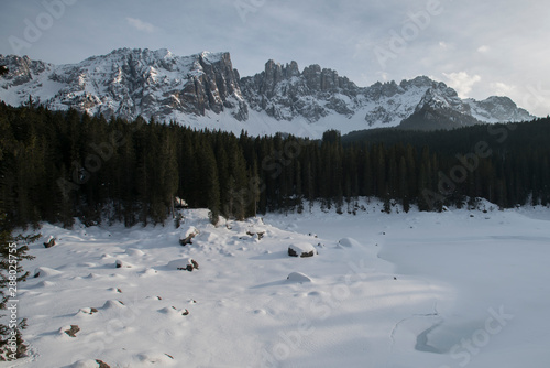 Karrersee, Lago di Carezza in Winter with Latemar covered in Snow in the Background. Latemar Mountain range in the Dolomites in South tirol, Südtirol photo