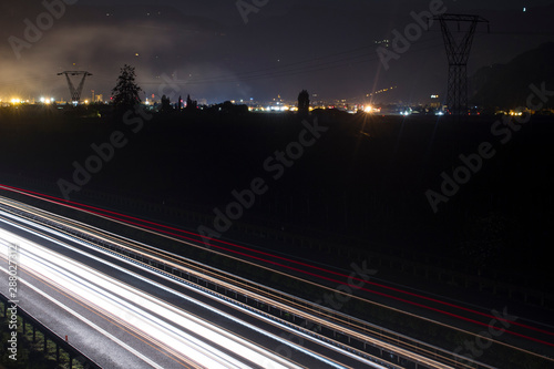 Two side Traffic on the A22 Autobahn in South Tirol, Bolzano in the Background. Long exposure of Light trails at night. photo