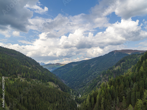 Beautiful V shaped Valley in the Alps, sides of the Valley covered by thick Forests and Mountains in the Background © Rabanser