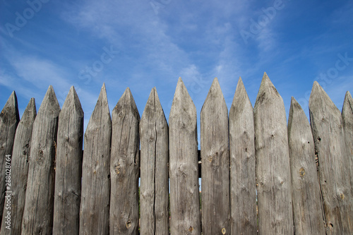 Close up on an old fence made of logs, Protective structure for the protection of a wooden fortress. Fence and strengthening of the ancient medieval fortress fence of sharpened wooden logs.