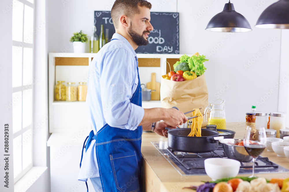 Smiling and confident chef standing in large kitchen Smiling and confident chef standing in large kitchen