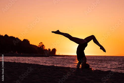 Flexible woman practicing yoga on the beach during sunset  relaxation  wellbeing  zen attitude  healthy