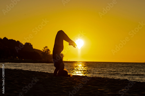 Flexible woman practicing yoga and gymnastics on the beach at sunset in scorpion poses, relaxation, wellbeing, good posture, zen attitude, healthy, ocean pacific view