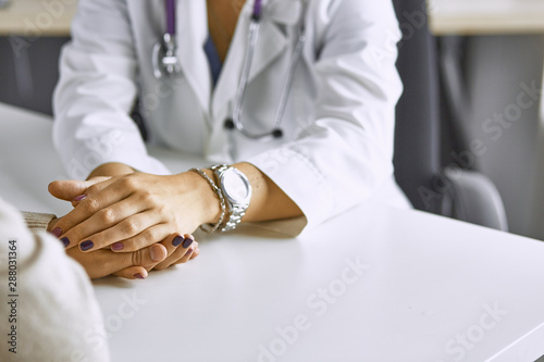 Woman doctor calms patient and holds hand