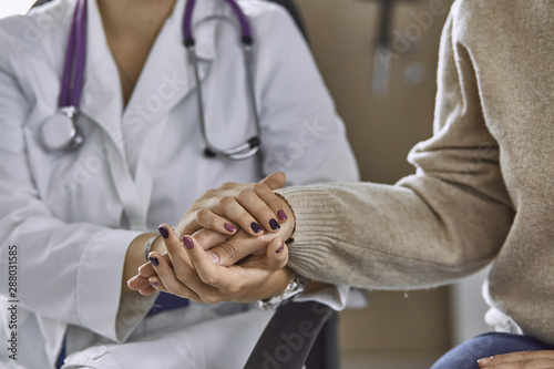 Woman doctor calms patient and holds hand