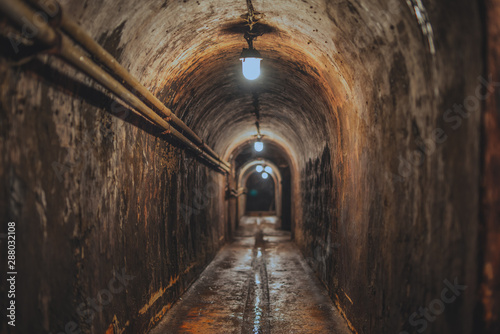 long dark narrow underground tunnel with lighting