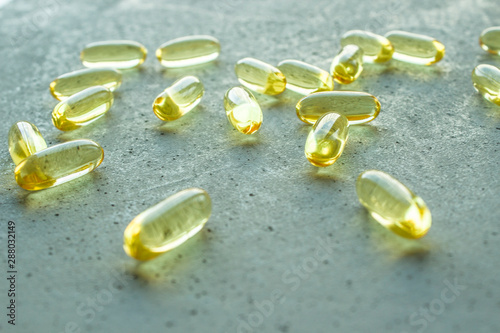 yellow transparent oval capsule vitamins pills on gray concrete background