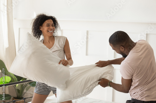 Young family couple having fun with pillow fighting.