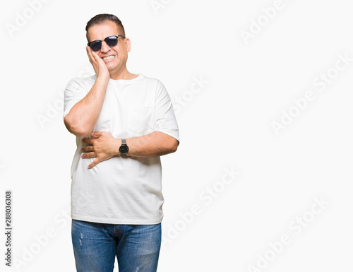 Middle age arab man wearig white t-shirt and sunglasses over isolated background thinking looking tired and bored with depression problems with crossed arms. photo