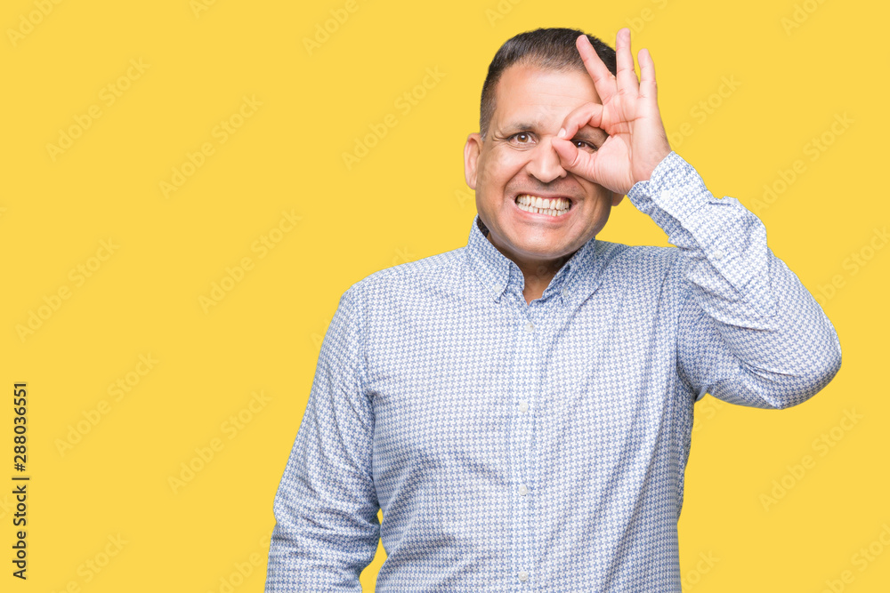 Middle age arab business man over isolated background doing ok gesture with hand smiling, eye looking through fingers with happy face. Middle age arab business man over isolated background doing ok gesture with hand smiling, eye looking through fingers with happy face.
