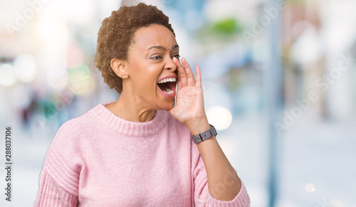 Beautiful young african american woman over isolated background shouting and screaming loud to side with hand on mouth. Communication concept.