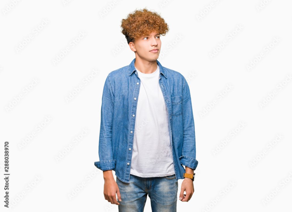 Young handsome man with afro hair wearing denim jacket smiling looking side and staring away thinking. Young handsome man with afro hair wearing denim jacket smiling looking side and staring away thinking.