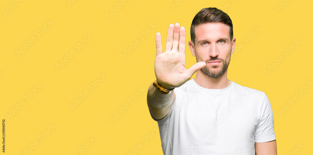 Handsome man wearing casual white t-shirt doing stop sing with palm of the hand. Warning expression with negative and serious gesture on the face. Handsome man wearing casual white t-shirt doing stop sing with palm of the hand. Warning expression with negative and serious gesture on the face.