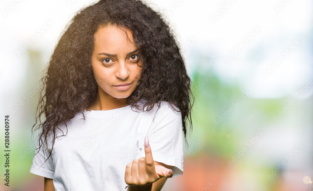 Young beautiful girl with curly hair wearing casual white t-shirt Beckoning come here gesture with hand inviting happy and smiling